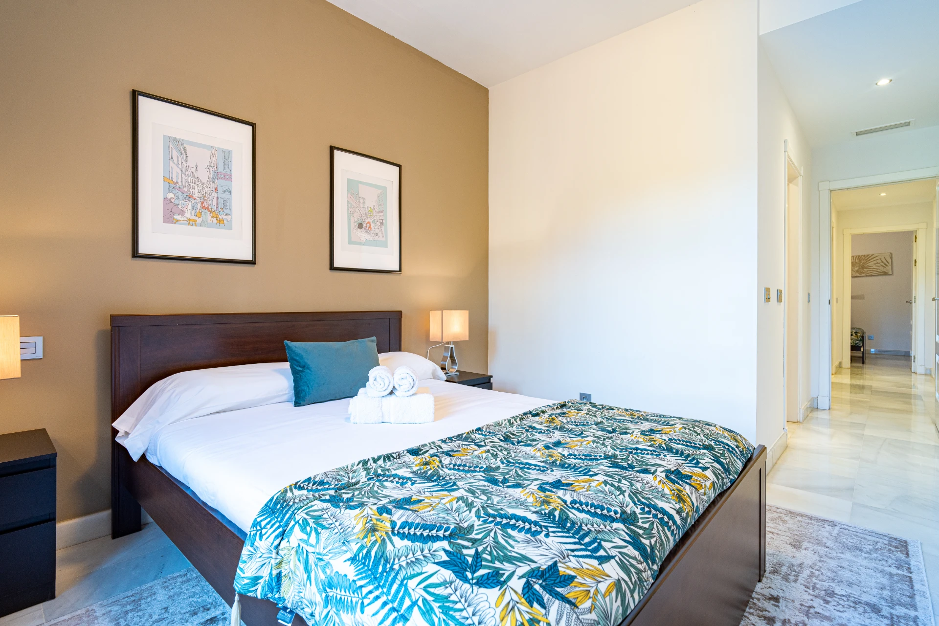 Comfortable double bedroom with modern decor, featuring a patterned bedspread, decorative pillows, and framed artwork, highlighting a serene atmosphere ideal for a vacation rental in Marbella.